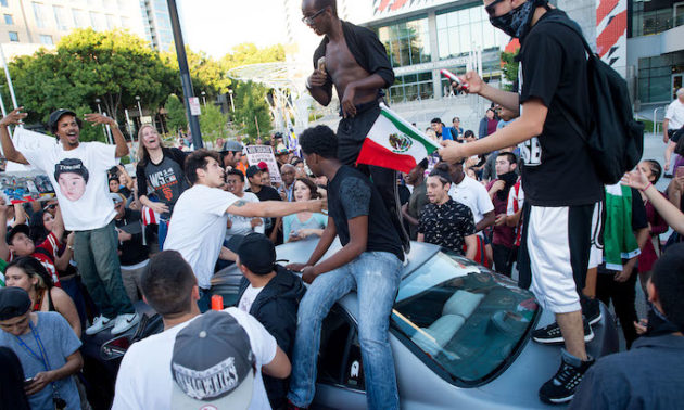 Protesters against Republican presidential candidate Donald Trump climb on a car outside a Trump campaign rally on Thursday, June 2, 2016, in San Jose, Calif. A group of protesters attacked Trump supporters who were leaving the candidate&apos;s rally in San Jose on Thursday night. A dozen or more people were punched, at least one person was pelted with an egg and Trump hats grabbed from supporters were set on fire on the ground. (AP Photo/Noah Berger)