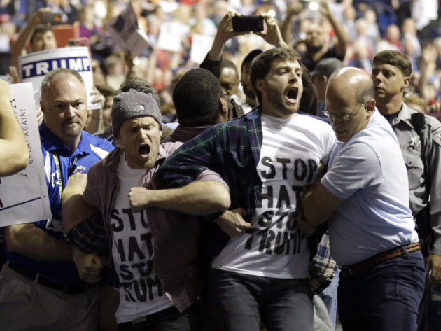 FILE - In this Wednesday, March 9, 2016 file photo, protesters are removed as Republican presidential candidate Donald Trump speaks during a campaign rally in Fayetteville, N.C. Authorities in North Carolina say they are looking at Trumps behavior as they continue their probe of a violent altercation at one of his rallies last week. The Cumberland County Sheriffs Office said in a March 14 statement that its investigators are continuing to look at the rally in Fayetteville, during which a man was hit in the face while being escorted out. (AP Photo/Gerry Broome)